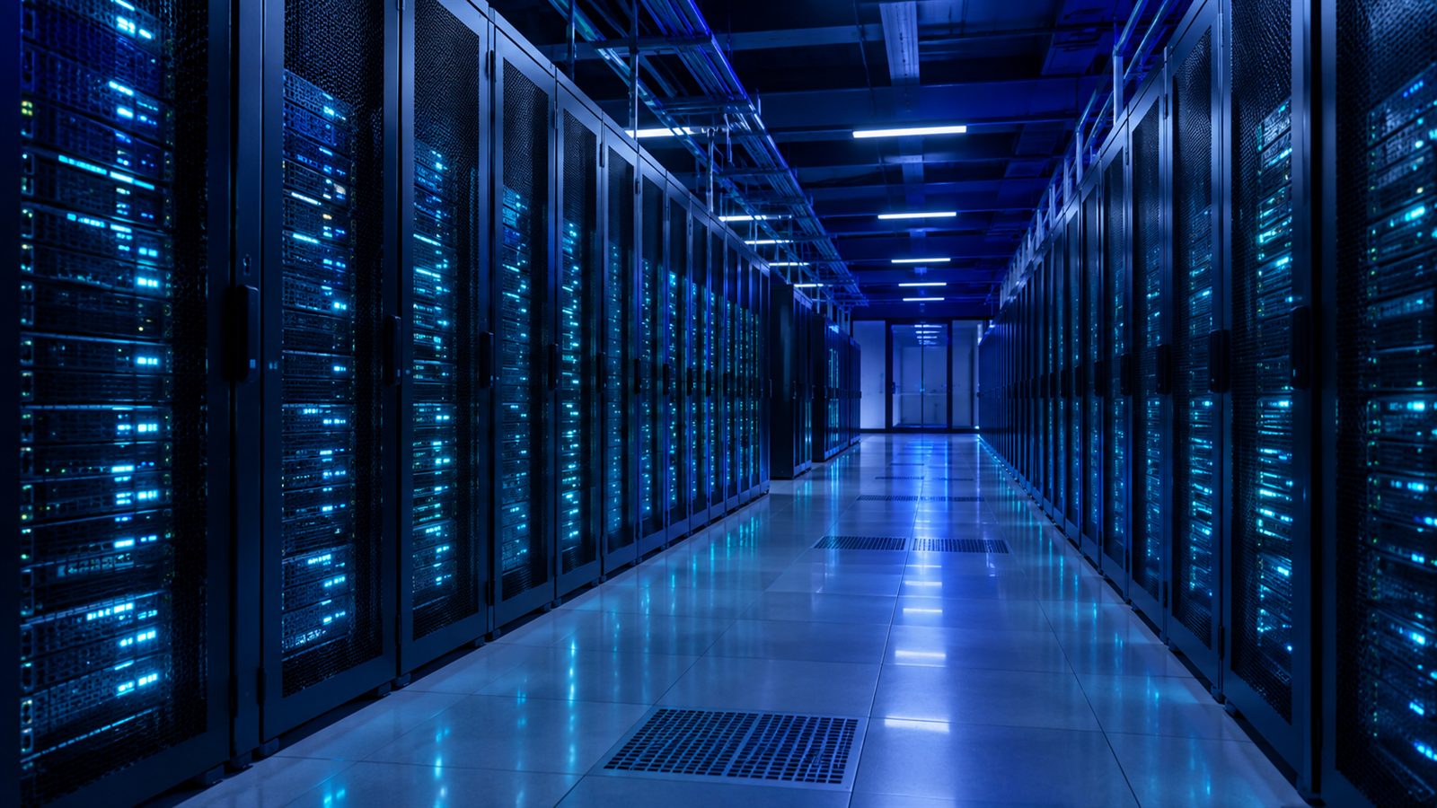 A wide datacenter corridor with converging rows of server racks and cyan LED lights